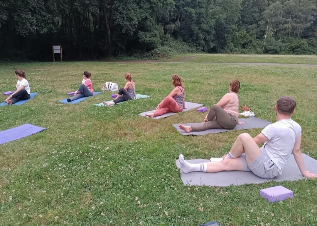 Cours de yoga en extérieur, groupe assis en cercle sur l’herbe